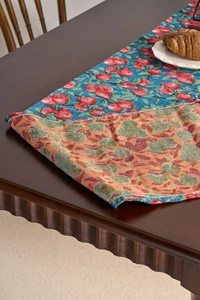 Close-up of jacquard table runner with red cherry pattern on a rustic wooden dining table