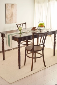Detailed view of dark wood dining table leg with vertical grooves and textured tassels