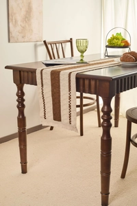 Detail of Nordic table runner with brown stripes and delicate fringe on wooden table