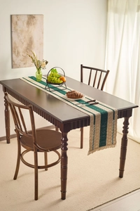 Detail of dark green and beige striped woven table runner with rustic fringe tassels