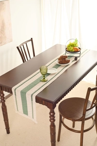 Close-up of Nordic table runner with green white stripes and handmade tassels