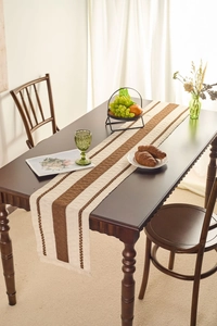 Detail of Nordic striped table runner with fringe on a dark wooden dining table