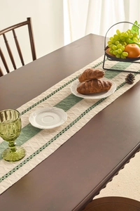 Close-up of vintage green and cream striped knit table runner with delicate lace edges