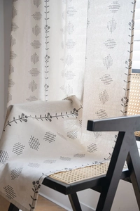 Detail of floral printed cream curtain fabric with geometric diamond patterns and natural drape
