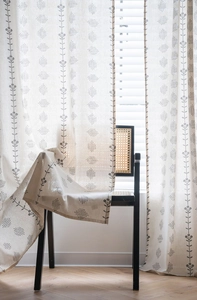 Detail of Nordic linen curtain with gray floral print on beige fabric over a chair