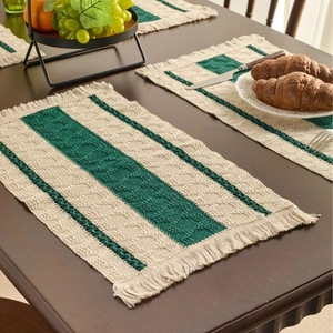 Bohemian woven table runner in retro green stripes with tassels on a wooden dining table