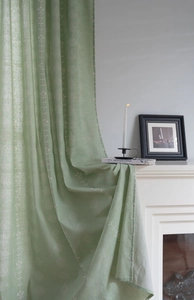 Detail view of sage green curtains with white floral patterns and dotted circle design