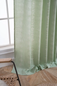 Detailed close-up of sage green floral curtains with white prints and textured lines