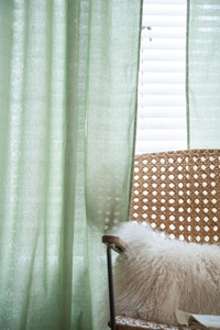 Close-up of sage green semi-sheer curtain with white floral vine embroidery detail