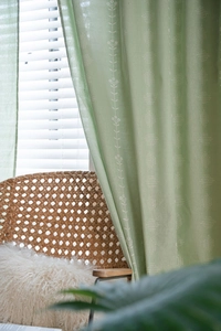 Detail of sage green floral curtain fabric showing breathable linen texture and patterns