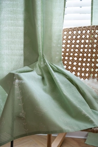 Close-up of sage green floral curtain fabric with white geometric lines and botanicals
