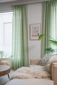 Close-up of sage green semi-sheer curtains with white floral patterns and rod pocket header