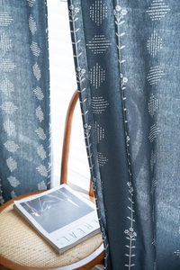 Navy blue linen-textured curtain with white floral print in a minimalist cozy home setting
