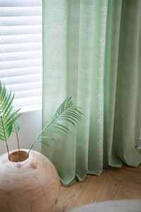 Detail of sage green floral curtain with white geometric patterns and natural linen texture