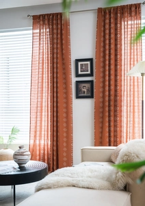 Détail de rideaux orange avec motifs géométriques blancs dans un salon chaleureux