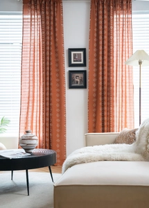 Détail de rideaux terracotta avec motif floral blanc dans une ambiance de salon chic