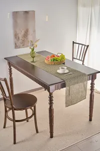 Close-up of light brown paper woven table runner with decorative tassel edge on wood
