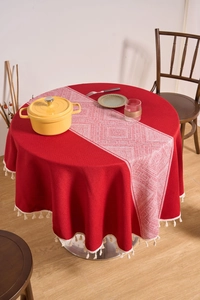 Detail of red cotton linen round tablecloth with white tassels and geometric runner