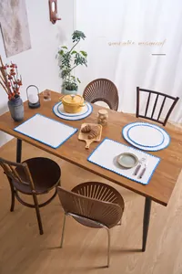 Close-up of modern white cotton linen placemat with blue embroidered shell pattern edges