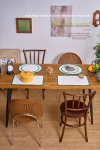 Close-up of white cotton linen placemat with green shell embroidery on a wooden table