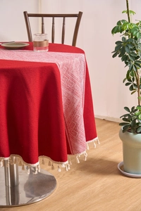 Close-up of red cotton linen round tablecloth featuring white tassels and geometric patterns