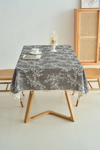 Detail of dark grey floral tablecloth with white print and elegant cream tassel edge