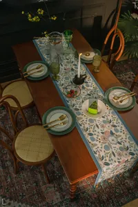 Close-up of retro floral table runner featuring blue woven borders and handmade tassels