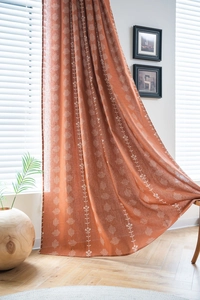 Détail du rideau orange avec imprimés floraux et motifs géométriques semi-occultants