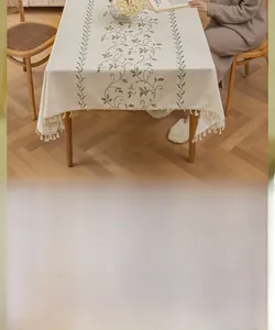 Close-up of rustic cotton linen tablecloth with green vine embroidery and white tassels