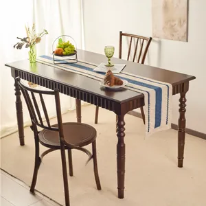 Detail of blue striped linen table runner with tassels on a dark wood dining table