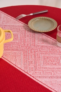 Detail of red and white geometric table runner on a festive cotton linen tablecloth