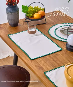 Close-up of cream placemat with green embroidery on natural linen-polyester fabric