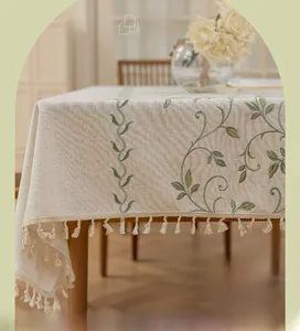 Detail of embroidered green vines and tassels on rectangular linen cotton tablecloth