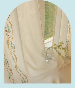 Détail de rideaux en coton lin beige avec broderies florales et bords à franges