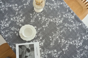 Macro detail of dark grey tablecloth with white leaf prints and fine woven texture