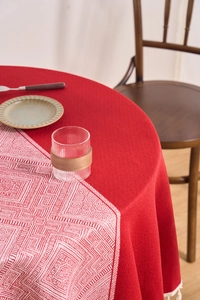 Close-up of red linen tablecloth with white tassels and geometric table runner detail