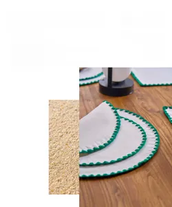Detail of round white cotton linen placemats with green scalloped embroidered borders