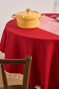 Detail of red cotton linen round tablecloth featuring elegant white cotton fringe tassels