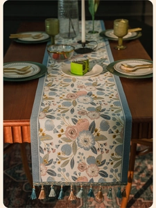 Macro detail of pastoral floral jacquard table runner with decorative tassel fringe edges