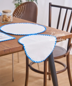 Close-up of exquisite blue floral embroidery on a white canvas round placemat