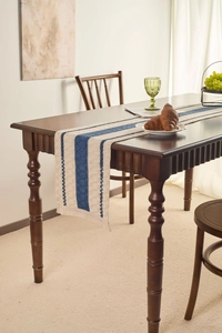 Detail of blue striped linen table runner with tassels on dark wood dining table