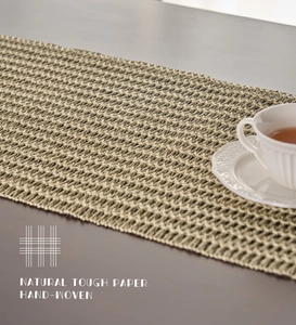 Close-up of hand-woven beige paper rope table runner with intricate hollow patterns