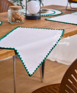 Detailed close-up of cream placemat with exquisite green crochet embroidery edges