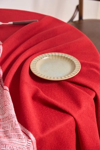 Detail of red cotton linen tablecloth featuring white geometric pattern border and textured weave