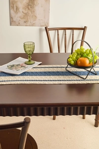 Detailed texture of blue and white striped knitted table runner on a dark wood table