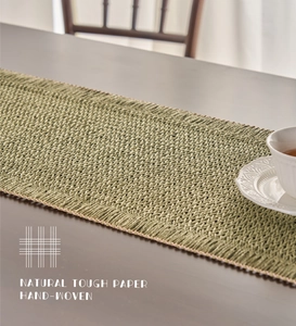 Close-up of green hand-woven paper table runner with detailed natural fiber texture