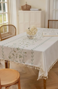 Close-up of green vine embroidery and fringe detail on minimalist linen tablecloth
