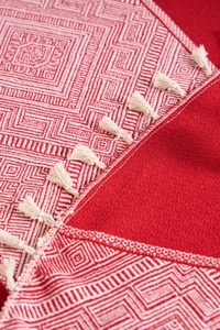 Macro detail of red cotton linen tablecloth with white geometric pattern and fringe trim
