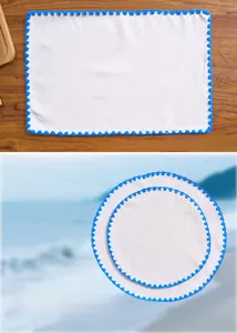Detail of white cotton linen placemat with blue pom-pom lace and soft ripple texture