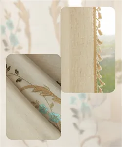 Détail du rideau en lin crème avec broderie florale et bordures à pompons
